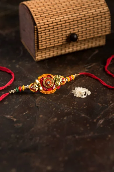 Raksha Bandhan-bakgrunn med en elegant Rakhi, Rice Grains, Kumkum og gaveboks. Et tradisjonelt indisk armbånd som symboliserer kjærlighet mellom brødre og søstre . – stockfoto