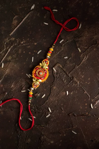 Raksha Bandhan background with an elegant Rakhi and scattered rice. A traditional Indian wrist band which is a symbol of love between Brothers and Sisters. — Stock Photo, Image