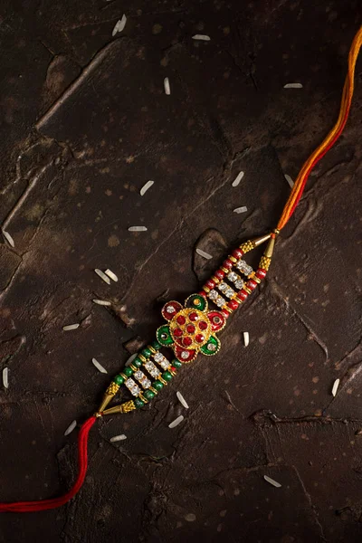 Raksha Bandhan background with an elegant Rakhi and scattered rice. A traditional Indian wrist band which is a symbol of love between Brothers and Sisters. — Stock Photo, Image