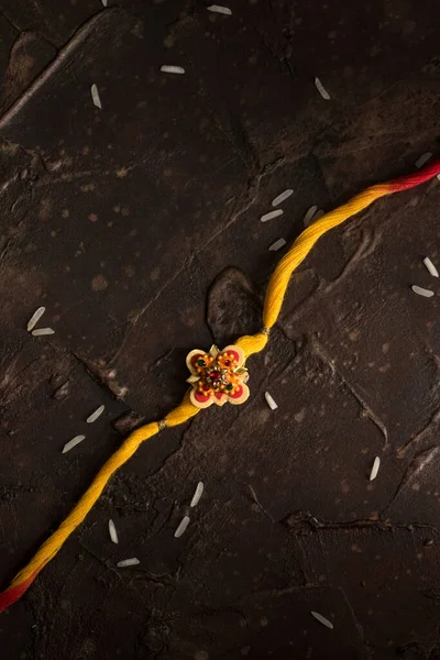 Raksha Bandhan background with an elegant Rakhi and scattered rice. A traditional Indian wrist band which is a symbol of love between Brothers and Sisters. — Stock Photo, Image