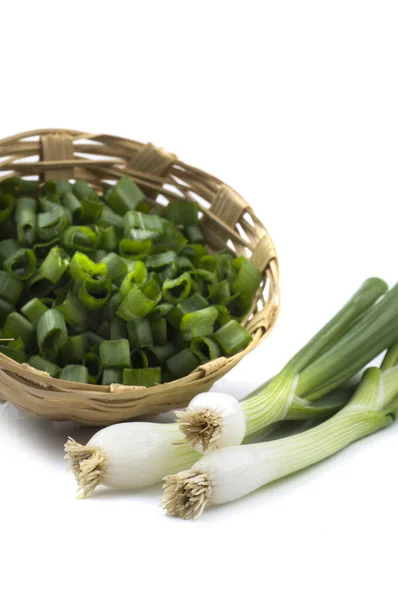Čerstvé zralé zelené jarní cibule (šalotka nebo hřebenatky) s nasekanou cibulí v košíku na bílém pozadí — Stock fotografie