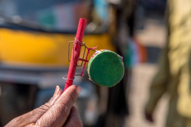 Amravati, Maharashtra, Hindistan, Ocak - 26, 2018: Renkli el yapımı geleneksel bebek çıngırağı (mini davul) satan tanımlanamayan sokak satıcısı. Kırsal Hindistan