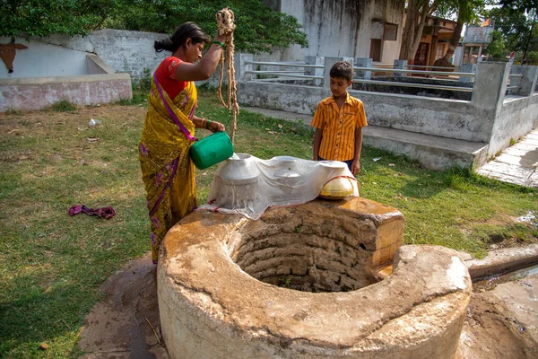 AMRAVATI, MAHARASHTRA, INDIA - 17 DE JUNIO DE 2017: Mujeres no identificadas y su hijo de la aldea recogen agua potable de un pozo . — Foto de Stock