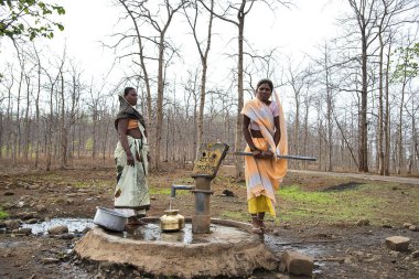 Amravati, Maharashtra, Hindistan, 11 Haziran 2017: Tanımlanamayan kırsal Hintli kadınlar geleneksel tencerelerde el pompasından su taşıyorlar, her gün kadınlar kuraklık nedeniyle birkaç kilometre yürüyorlar.