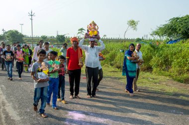 Amravati, Maharashtra, Hindistan - 23 Eylül 2018: Ganesh festivali sırasında Hindu Tanrısı Ganesha 'yı suya batırılmadan önce taşıyan tanımlanamayan inançlı insanlar. Yıllık festival.