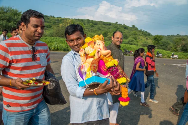 Amravati, Maharashtra, Hindistan - 23 Eylül 2018: Ganesh festivali sırasında Hindu Tanrısı Ganesha 'yı suya batırılmadan önce taşıyan tanımlanamayan inançlı insanlar. Yıllık festival. — Stok fotoğraf