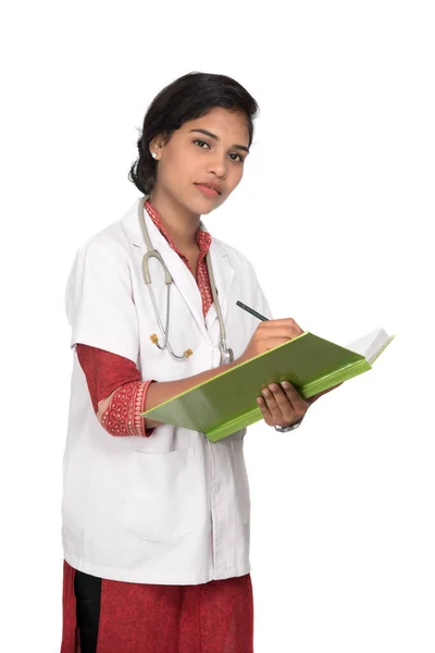 청진기를 사용하는 젊은 여성 의사가 책을 쓰고 있습니다 — 스톡 사진