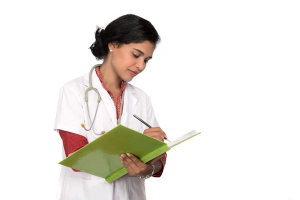 Mujer joven médico con estetoscopio está escribiendo en el libro —  Fotos de Stock