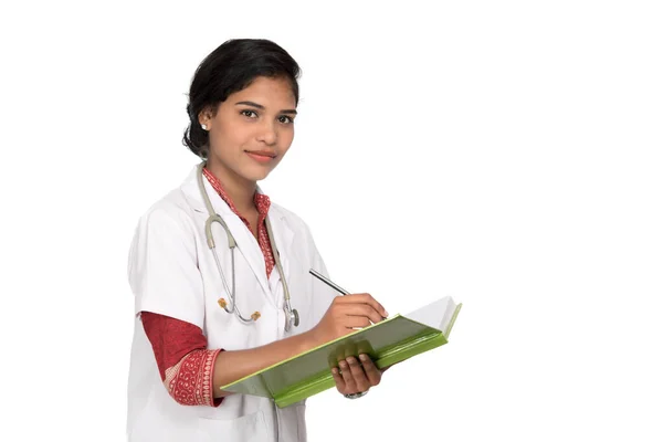 Mujer joven médico con estetoscopio está escribiendo en el libro —  Fotos de Stock