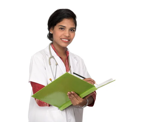 Mujer joven médico con estetoscopio está escribiendo en el libro —  Fotos de Stock