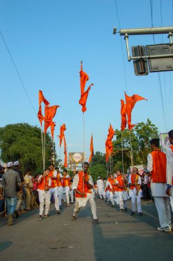 Amravati, Maharashtra, Hindistan - 27 Eylül 2018: Ganesh batışı sırasında geleneksel davul çalan bir grup insanın önünde bayrak sallayan ve dans eden bir adam. Ganesha Chaturthi.