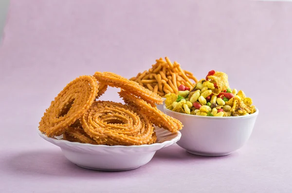 Indischer Imbiss: chakli, chakali oder murukku und besan (Gramm Mehl) sev und chivada oder chiwada auf rosa Hintergrund. Diwali-Essen — Stockfoto