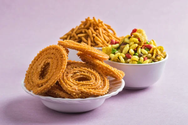 Indischer Imbiss: chakli, chakali oder murukku und besan (Gramm Mehl) sev und chivada oder chiwada auf rosa Hintergrund. Diwali-Essen — Stockfoto