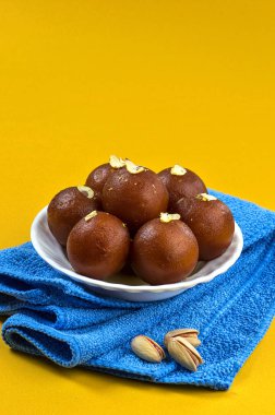 Gulab Jamun, beyaz kasede Hint tatlısı, içinde fıstık, badem ve peçeteli kaju var.