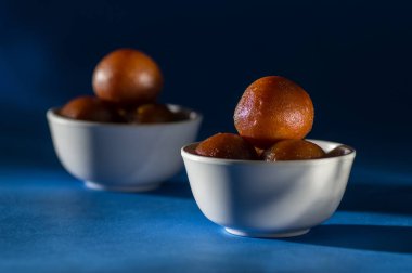 Hint Tatlısı: Gulab Jamun kasede mavi arka planda kaşıkla