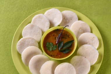 Sambar 'ın yeşil arka planda olduğu Idli, Hint Dili: Güney Hint yemekleri rava idli veya irmik ya da rava tembelce, sambar ve yeşil hindistan cevizi turşusuyla servis edilir..