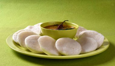 Sambar 'ın yeşil arka planda olduğu Idli, Hint Dili: Güney Hint yemekleri rava idli veya irmik ya da rava tembelce, sambar ve yeşil hindistan cevizi turşusuyla servis edilir..