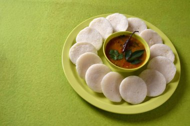 Sambar 'ın yeşil arka planda olduğu Idli, Hint Dili: Güney Hint yemekleri rava idli veya irmik ya da rava tembelce, sambar ve yeşil hindistan cevizi turşusuyla servis edilir..