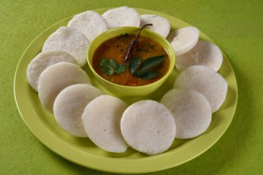 Sambar 'ın yeşil arka planda olduğu Idli, Hint Dili: Güney Hint yemekleri rava idli veya irmik ya da rava tembelce, sambar ve yeşil hindistan cevizi turşusuyla servis edilir..