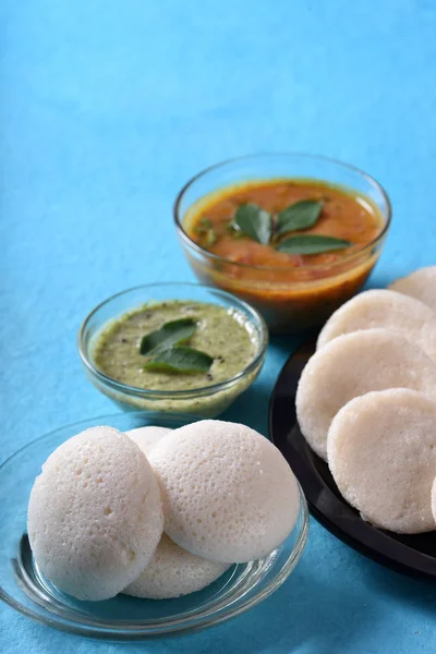 青色の背景にサンバーとココナッツチャツネとイドリ インド料理 南インドのお気に入りの食べ物のラバイドリまたはセモリナまたはラヴァをぼんやりと サンバーと緑のココナッツチャツネを添えて — ストック写真