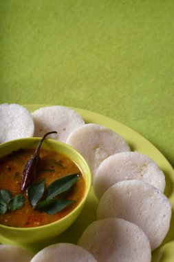 Sambar 'ın yeşil arka planda olduğu Idli, Hint Dili: Güney Hint yemekleri rava idli veya irmik ya da rava tembelce, sambar ve yeşil hindistan cevizi turşusuyla servis edilir..