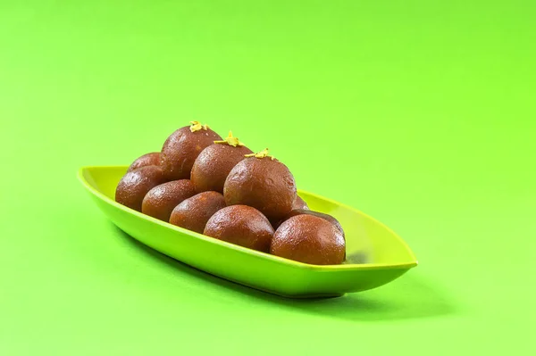 Gulab jamun im Teller auf grünem Hintergrund. indisches Dessert oder süßes Gericht. — Stockfoto
