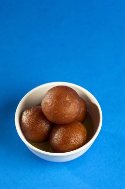 Hint Tatlısı: Gulab Jamun kasede mavi arka planda kaşıkla