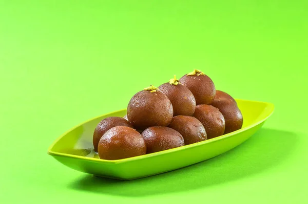Gulab jamun im Teller auf grünem Hintergrund. indisches Dessert oder süßes Gericht. — Stockfoto