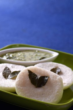 Mavi arka planda hindistan cevizi turşulu Idli, Hint yemeği: Güney Hint yemeği rava idli ya da irmik ya da rava aylak aylak, sambar ve yeşil hindistan cevizi turşusuyla servis edilir..