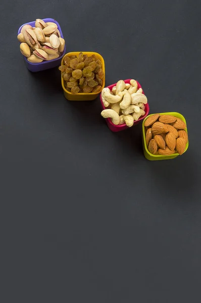 Healthy Mix Dry Fruits and Nuts on dark background. Almonds, Pistachio, Cashews, Raisins