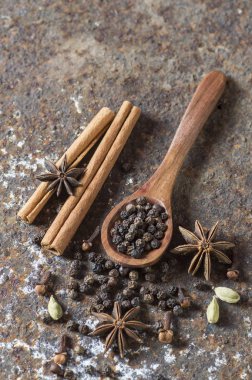 Baharatlar ve bitkiler. Yiyecek ve mutfak malzemeleri. Tarçın çubukları, anason yıldızları, karabiber ve dokulu arka planda kakule..