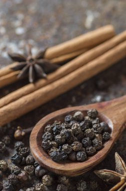 Baharatlar ve bitkiler. Yiyecek ve mutfak malzemeleri. Tarçın çubukları, anason yıldızları, karabiber ve dokulu arka planda kakule..
