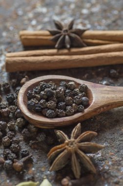 Baharatlar ve bitkiler. Yiyecek ve mutfak malzemeleri. Tarçın çubukları, anason yıldızları, karabiber ve dokulu arka planda kakule..