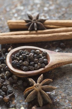Baharatlar ve bitkiler. Yiyecek ve mutfak malzemeleri. Tarçın çubukları, anason yıldızları, karabiber ve dokulu arka planda kakule..