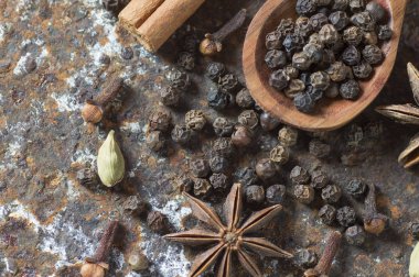 Baharatlar ve bitkiler. Yiyecek ve mutfak malzemeleri. Tarçın çubukları, anason yıldızları, karabiber ve dokulu arka planda kakule..