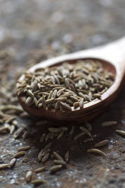 Ahşap kaşıkta kimyon tohumları dokulu bir arka planda