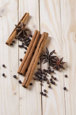 Baharatlar ve bitkiler. Yiyecek ve mutfak malzemeleri. Tarçın çubukları, anason yıldızları ve ahşap arka planda siyah biberler..
