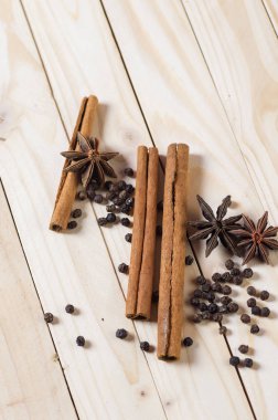 Baharatlar ve bitkiler. Yiyecek ve mutfak malzemeleri. Tarçın çubukları, anason yıldızları ve ahşap arka planda siyah biberler..