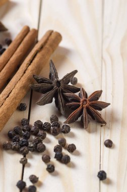 Baharatlar ve bitkiler. Yiyecek ve mutfak malzemeleri. Tarçın çubukları, anason yıldızları ve ahşap arka planda siyah biberler..