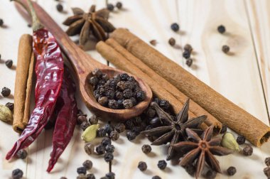 Baharatlar ve bitkiler. Yiyecek ve mutfak malzemeleri. Tarçın çubukları, anason yıldızları, siyah biberler, Chili, kakule ve karanfiller ahşap arka planda