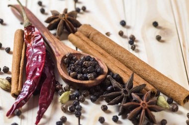 Baharatlar ve bitkiler. Yiyecek ve mutfak malzemeleri. Tarçın çubukları, anason yıldızları, siyah biberler, Chili, kakule ve karanfiller ahşap arka planda
