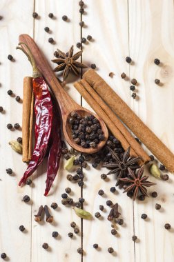 Baharatlar ve bitkiler. Yiyecek ve mutfak malzemeleri. Tarçın çubukları, anason yıldızları, siyah biberler, Chili, kakule ve karanfiller ahşap arka planda