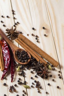 Baharatlar ve bitkiler. Yiyecek ve mutfak malzemeleri. Tarçın çubukları, anason yıldızları, siyah biberler, Chili, kakule ve karanfiller ahşap arka planda