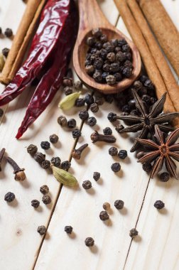 Baharatlar ve bitkiler. Yiyecek ve mutfak malzemeleri. Tarçın çubukları, anason yıldızları, siyah biberler, Chili, kakule ve karanfiller ahşap arka planda