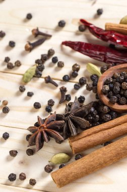 Baharatlar ve bitkiler. Yiyecek ve mutfak malzemeleri. Tarçın çubukları, anason yıldızları, siyah biberler, Chili, kakule ve karanfiller ahşap arka planda