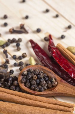 Baharatlar ve bitkiler. Yiyecek ve mutfak malzemeleri. Tarçın çubukları, anason yıldızları, siyah biberler, Chili, kakule ve karanfiller ahşap arka planda