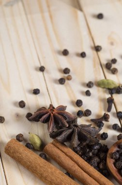 Baharatlar ve bitkiler. Yiyecek ve mutfak malzemeleri. Tarçın çubukları, anason yıldızları, siyah biberler, Chili, kakule ve karanfiller ahşap arka planda
