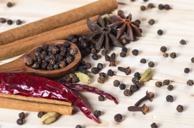 Baharatlar ve bitkiler. Yiyecek ve mutfak malzemeleri. Tarçın çubukları, anason yıldızları, siyah biberler, Chili, kakule ve karanfiller ahşap arka planda