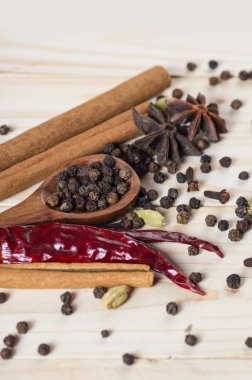 Baharatlar ve bitkiler. Yiyecek ve mutfak malzemeleri. Tarçın çubukları, anason yıldızları, siyah biberler, Chili, kakule ve karanfiller ahşap arka planda