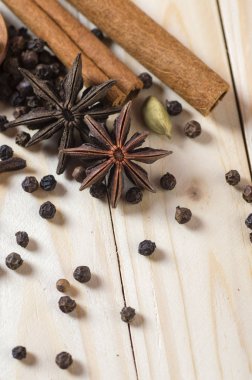 Baharatlar ve bitkiler. Yiyecek ve mutfak malzemeleri. Tarçın çubukları, anason yıldızları, siyah biberler, Chili, kakule ve karanfiller ahşap arka planda